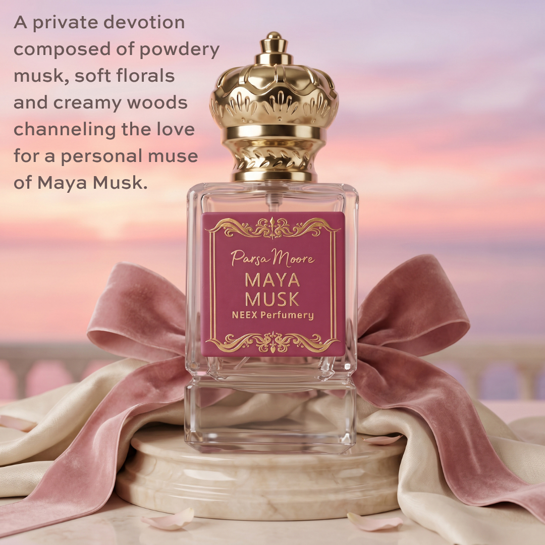 A rectangular glass perfume bottle with a gold crown cap and a pink label reading 'Parsa Moore MAYA MUSK NEEX Perfumery,' styled with a large pink satin bow and cream fabric against a soft pastel sky background. Product text appears on the left side.