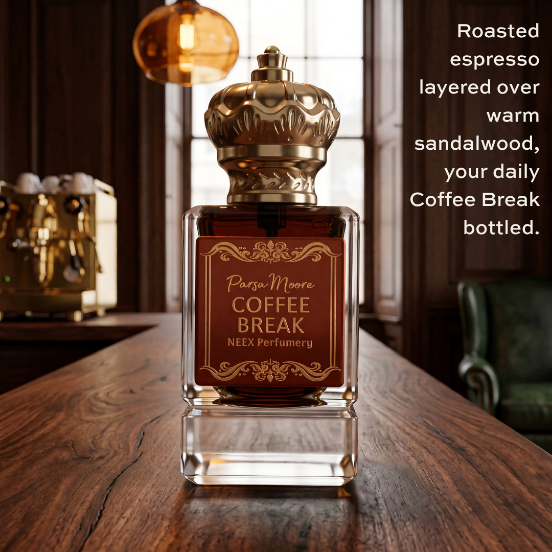 A clear glass perfume bottle with a metallic gold cap and a dark brown label reading 'Parsa Moore COFFEE BREAK NEEX Perfumery,' placed on a wooden table in a warm, dimly lit interior. Text on the right describes the scent as roasted espresso layered over warm sandalwood.