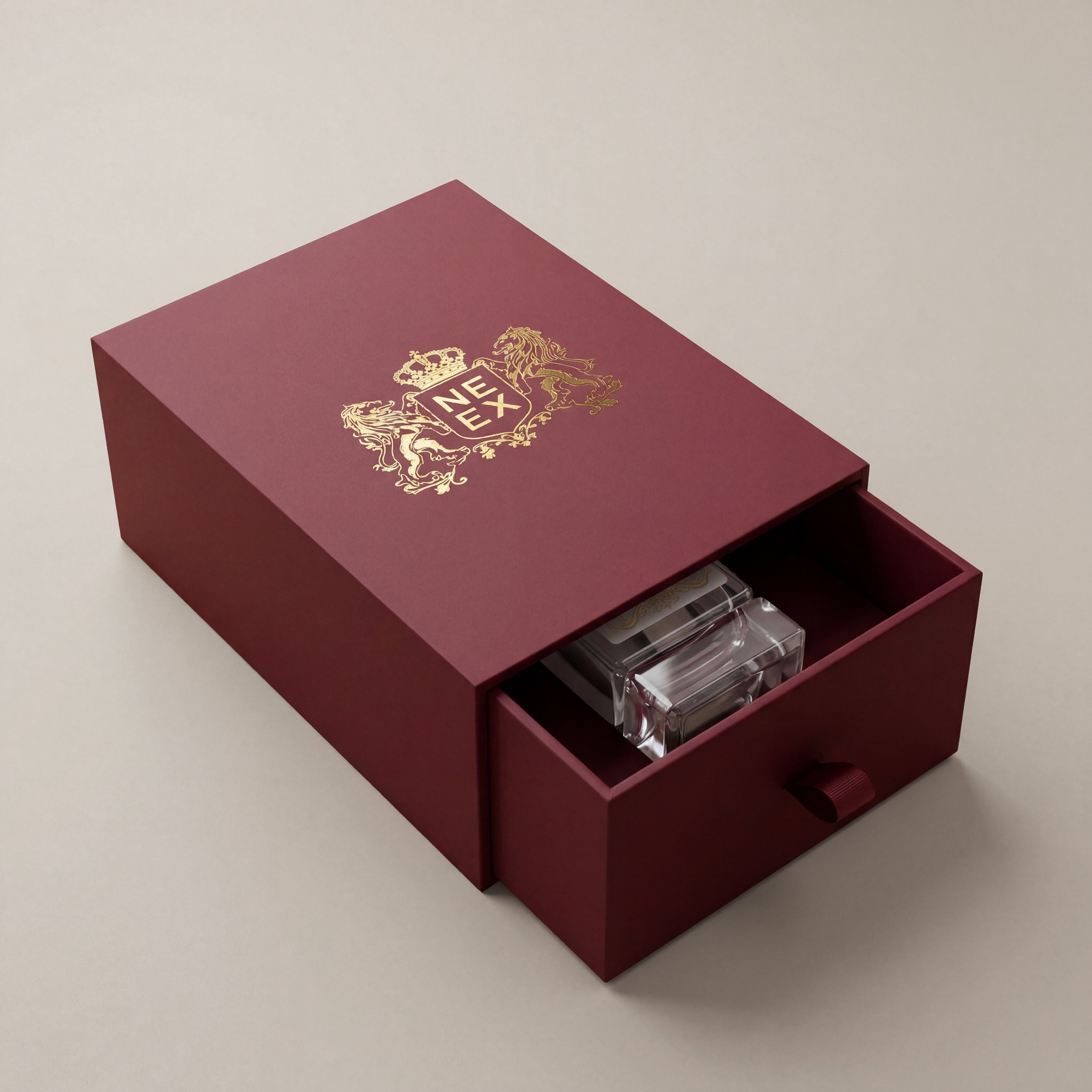 Maroon box with gold emblem and clear crystal inside on a beige background